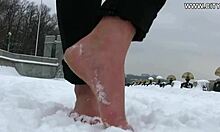 热情而性感的女人在雪地上赤裸着脚走着